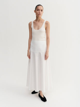 Woman wearing a white sleeveless top and skirt set on a plain background
